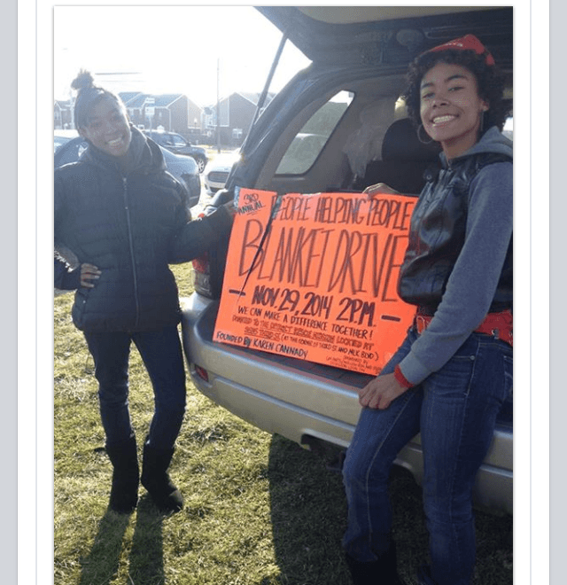 Volunteers holding the People Helping People Blanket Drive sign