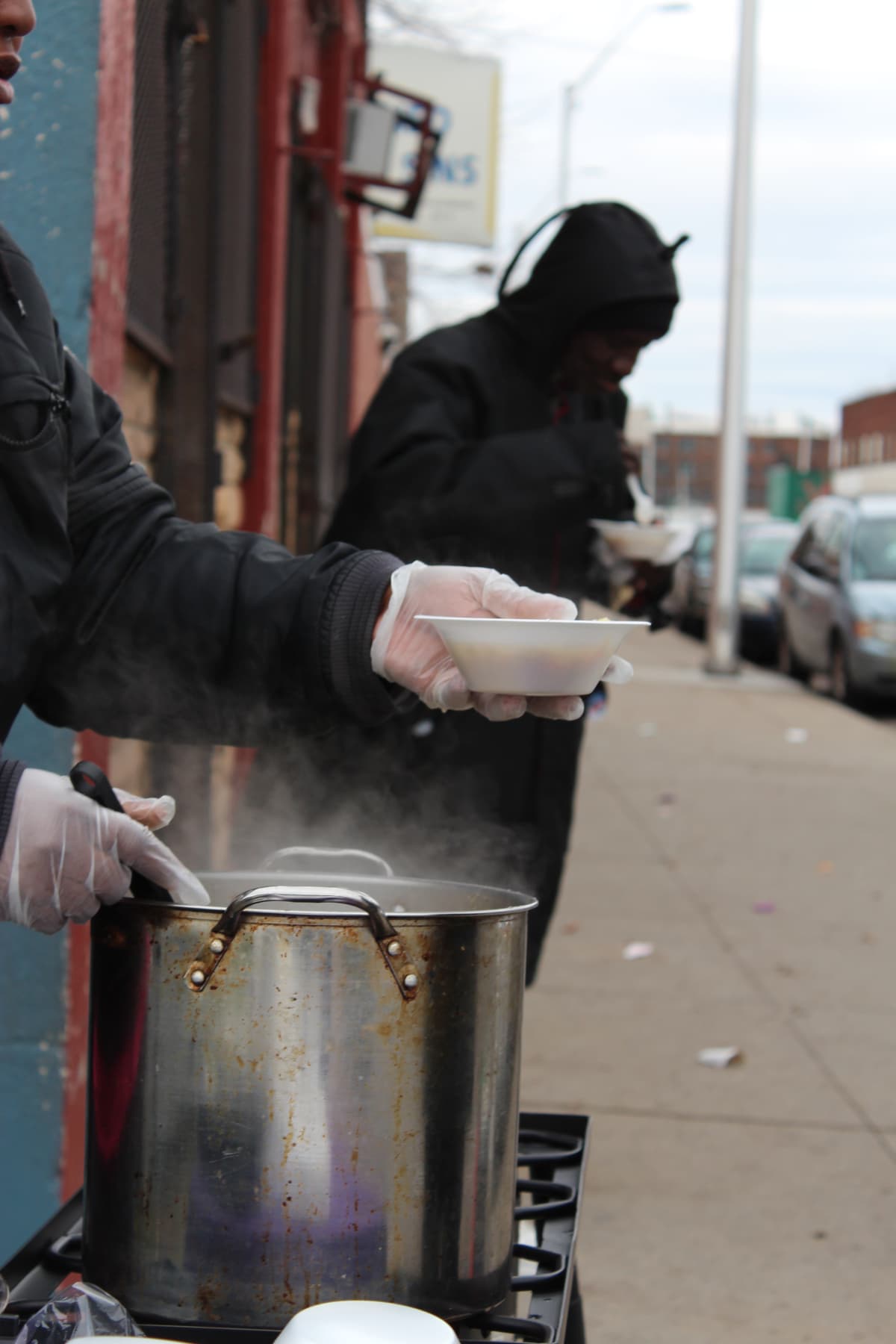 Serving hot soup — steam rising from the pot on distribution day
